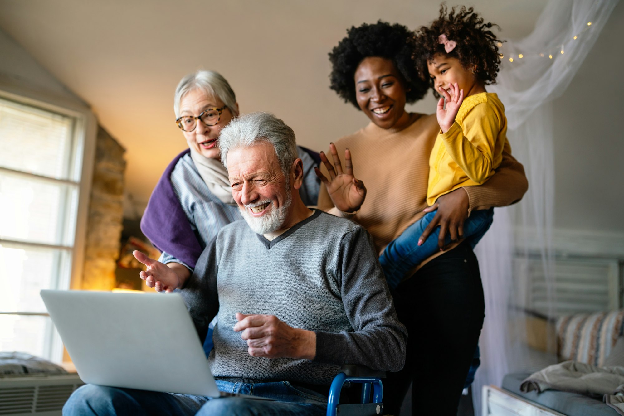 Happy multi-generation family gathering around notebbok and having fun during a video call